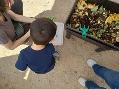 Imatge d'una criatura d'esquenes durant l'activitat amb una vermicompostadora.