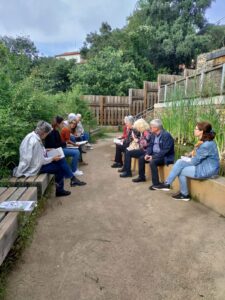 Fotografia de l'anterior lectura al bosc amb el grup de participants compartint reflexions a la vora de la bassa naturalitzada del Bosc Turull.